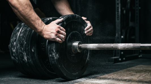 Loading a bumper plate onto a barbell for progressive overload training